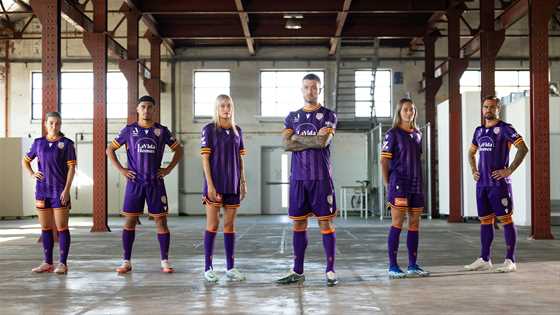 Group photo of 6 Perth Glory soccer players inside an empty warehouse