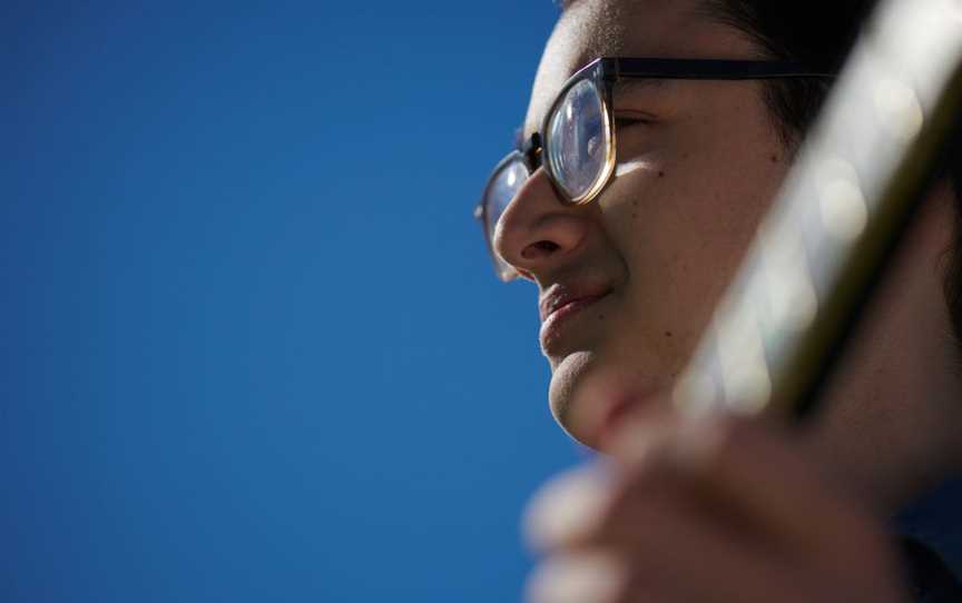 Perspective below a glasses-wearing man's face, who is holding a guitar