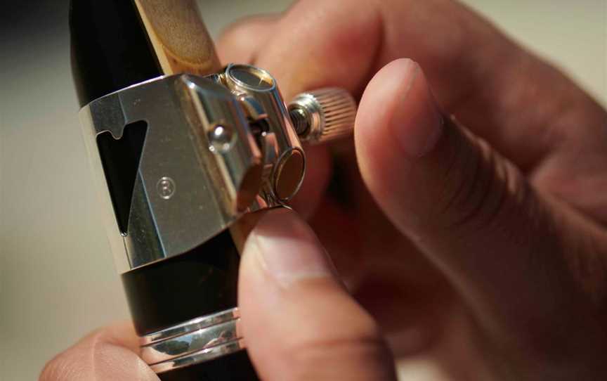 A close-up shot of someone adjusting their clarinet reed.