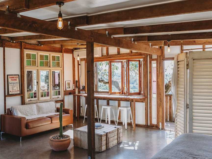 Bedroom and living area that opens out to the back deck and views over the valley. Luxe European linen on the queen bed, indoor bath, breakfast bar and cosy couch.